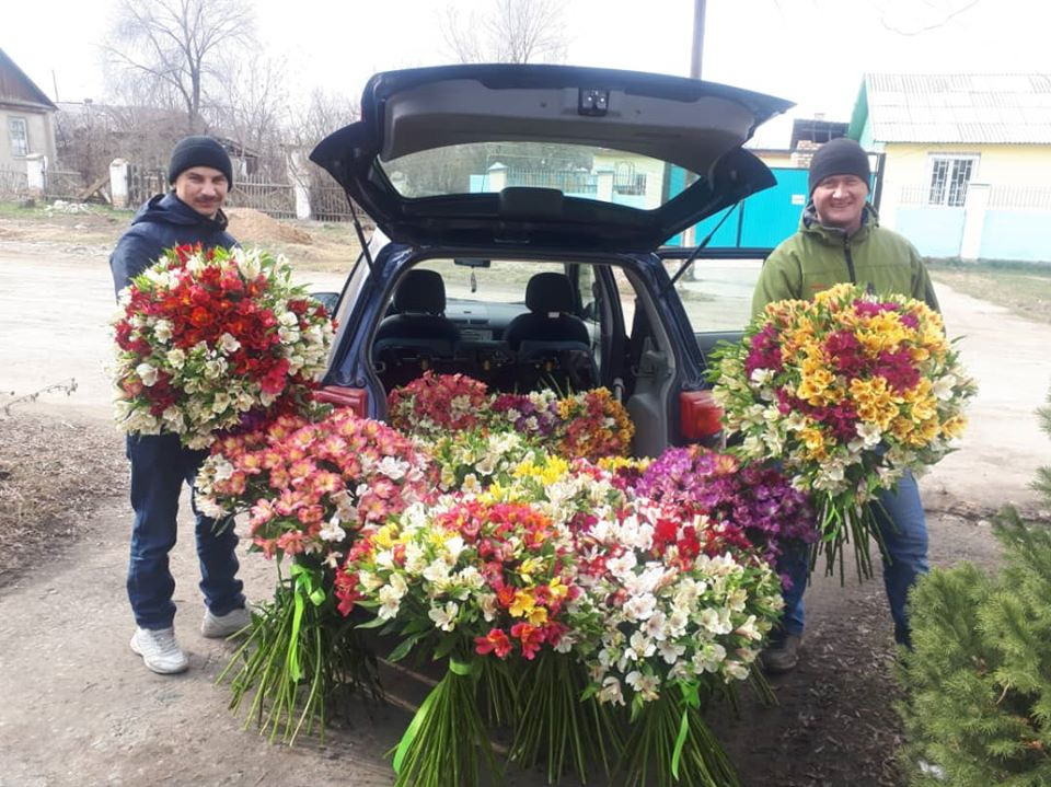 Выставка цветов в городе Каракол. Мужчина с огромным букетом цветов с машина. Какие цветы дарят погибшим. Фото букета в руках продавца.