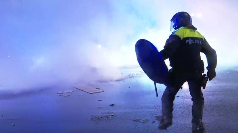 Столкновения в Гааге: в полицейского кидают камни из-за дымовой завесы.